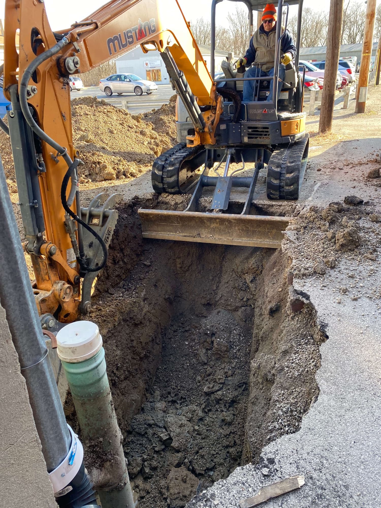 Mini excavator digging a trench to reach a sewer line