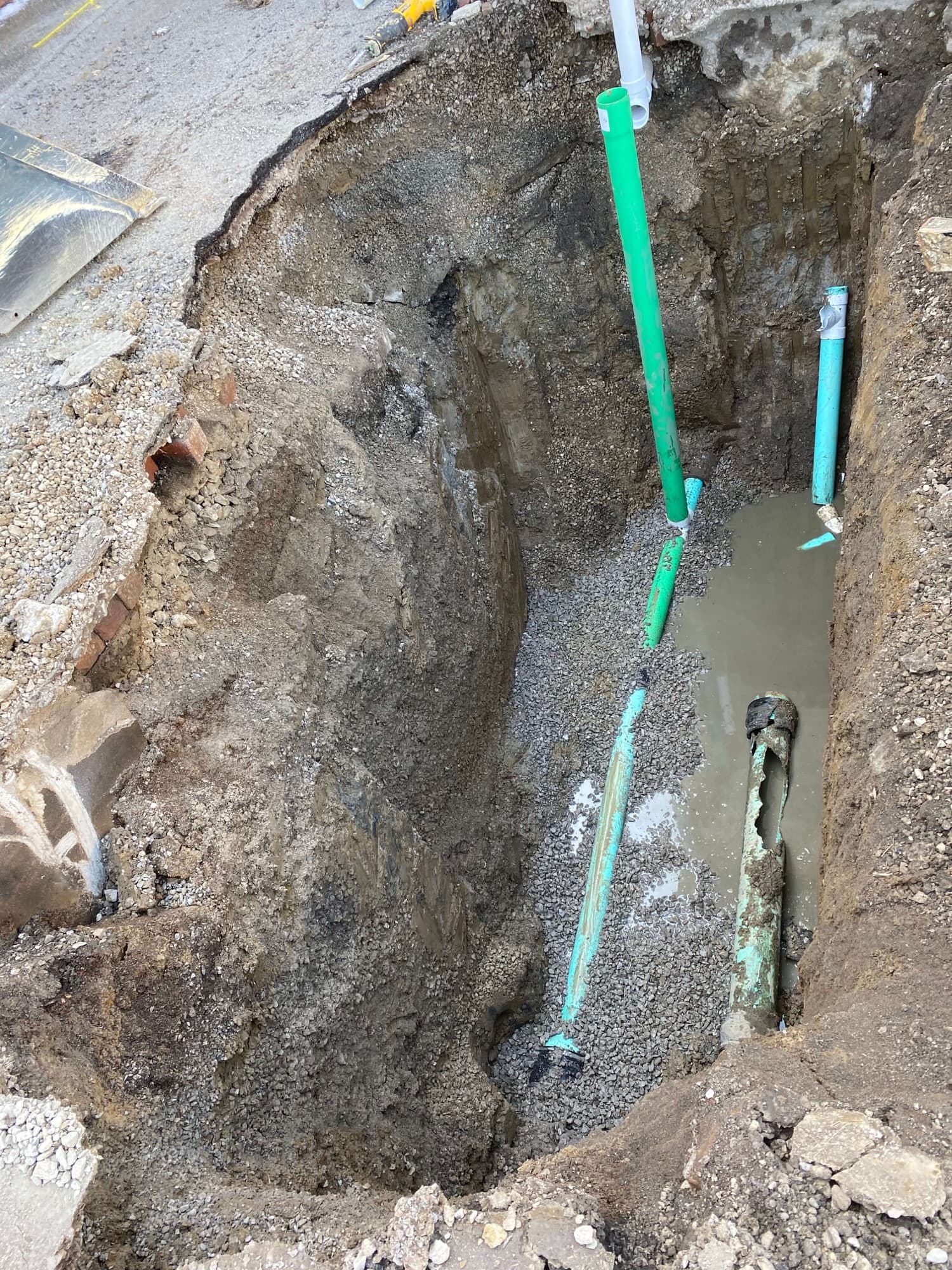 Excavated trench with exposed pipes during a line repair