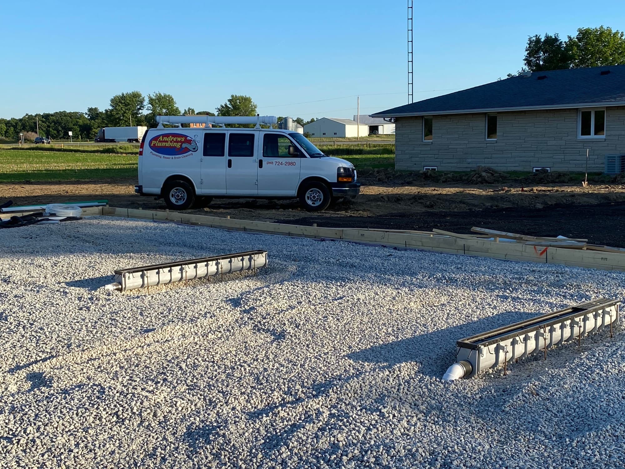 Andrews Plumbing van at a new-construction job site with underground plumbing in place