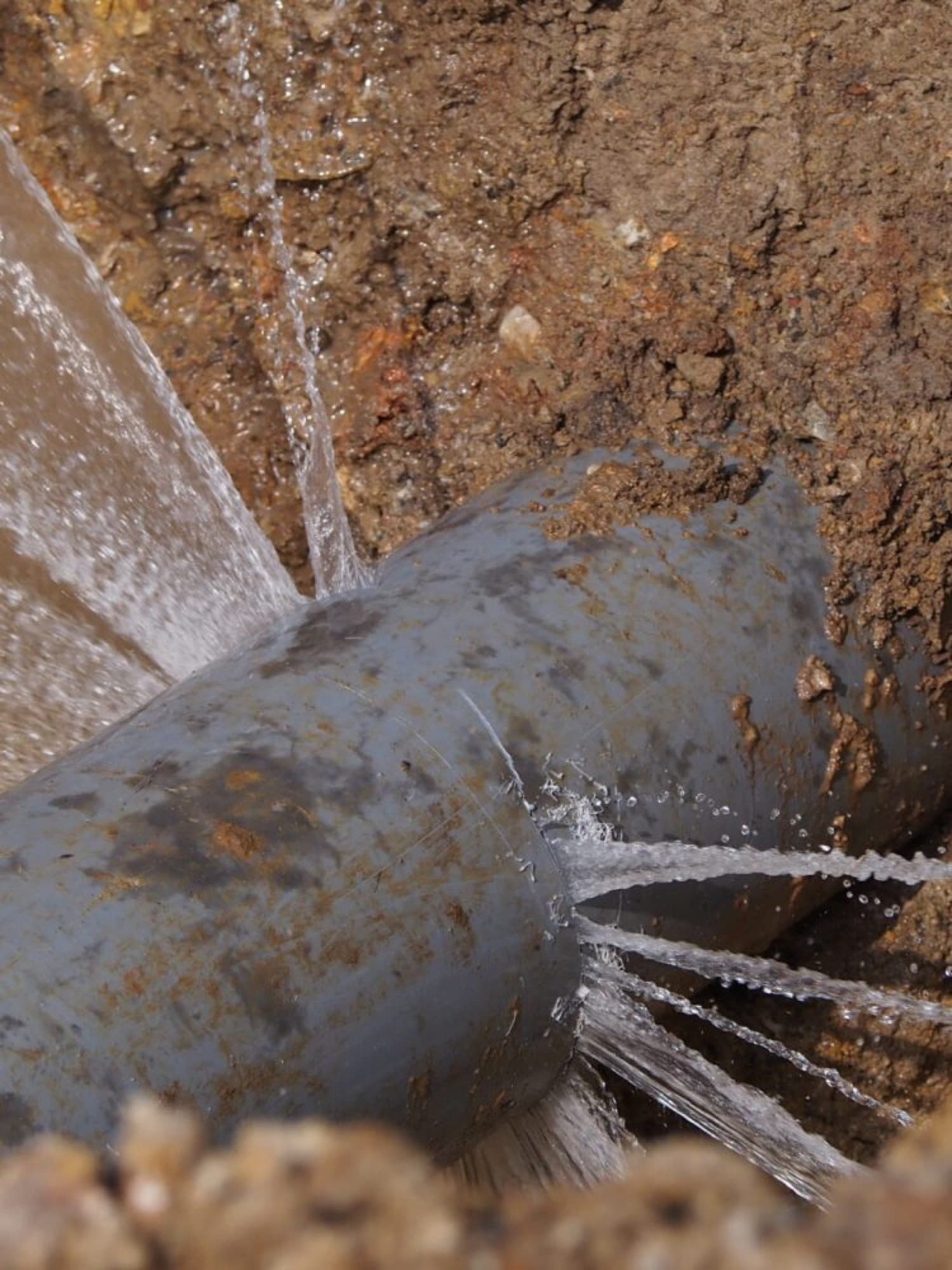 Burst pipe spraying water in an excavation